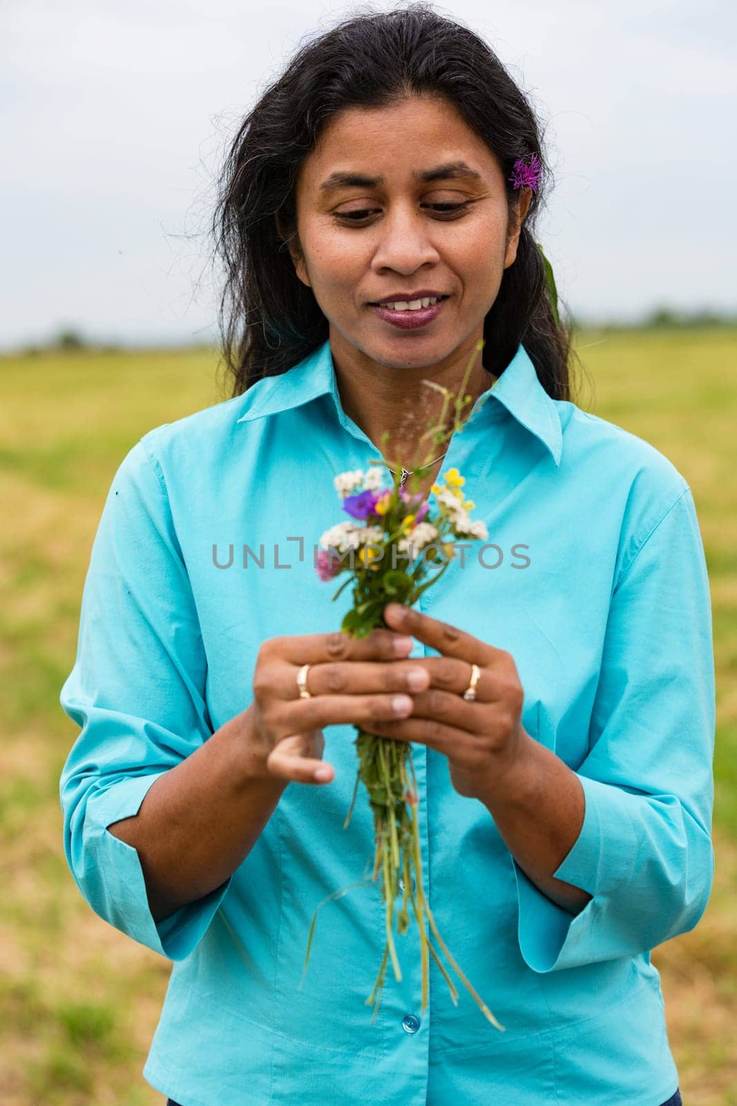 Attractive woman with self-picked flowers on summer meadow