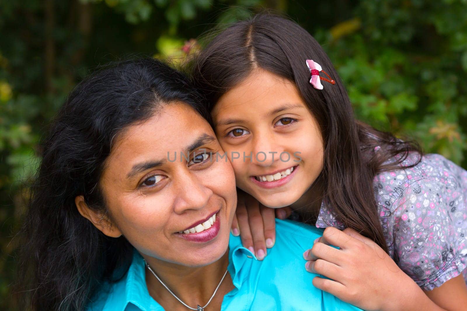 Mother hugs her daughter in summer