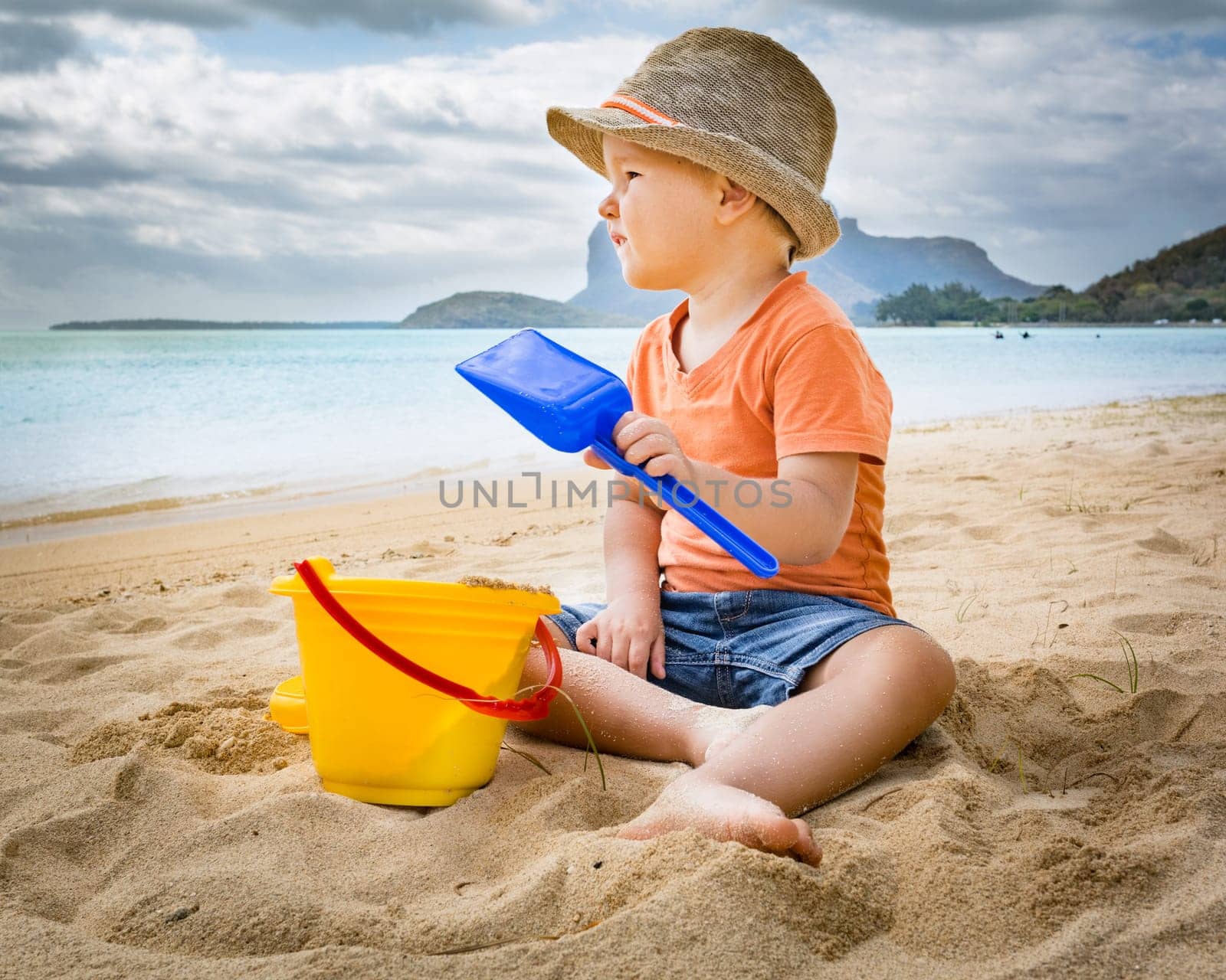 Cute boy on the tropical beach playing toys