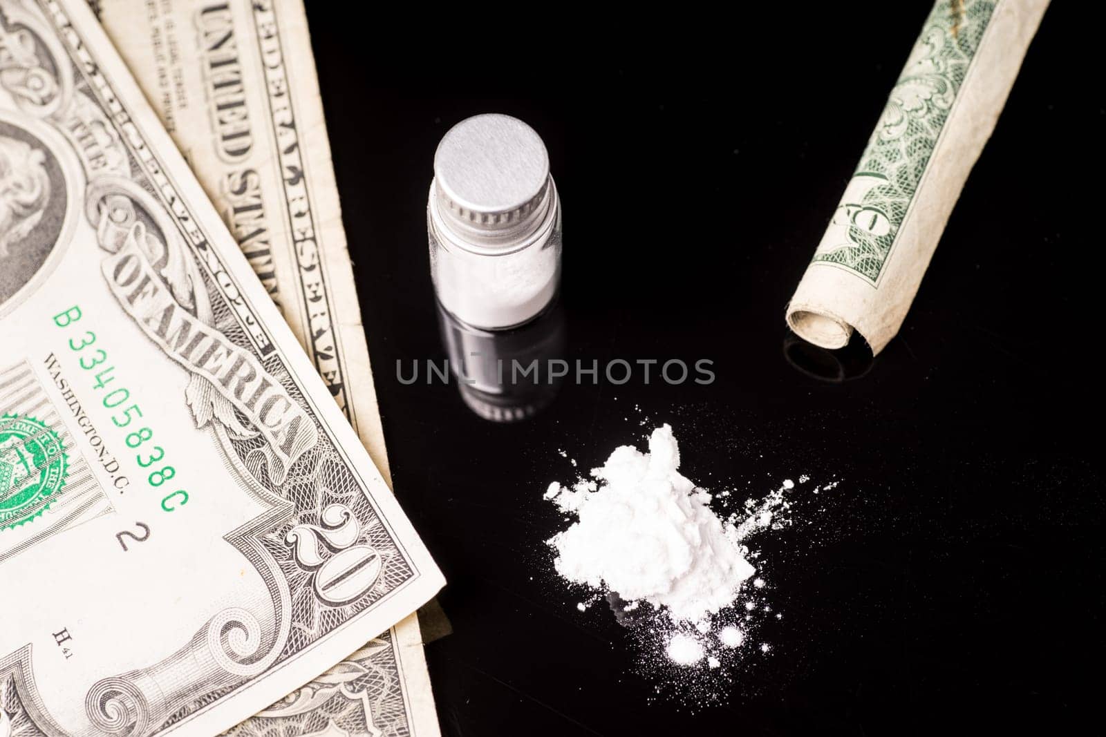 cocaine or other illegal drugs that are sniffed by means of a tube, isolated on black glossy background