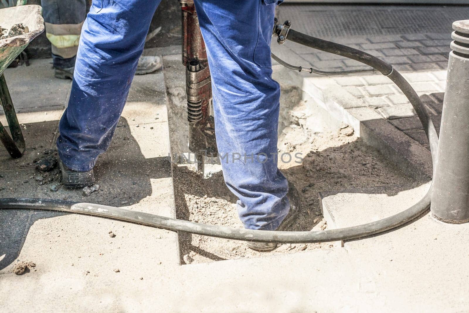 Builder worker with pneumatic hammer drill equipment breaking sidewalk asphalt on street
