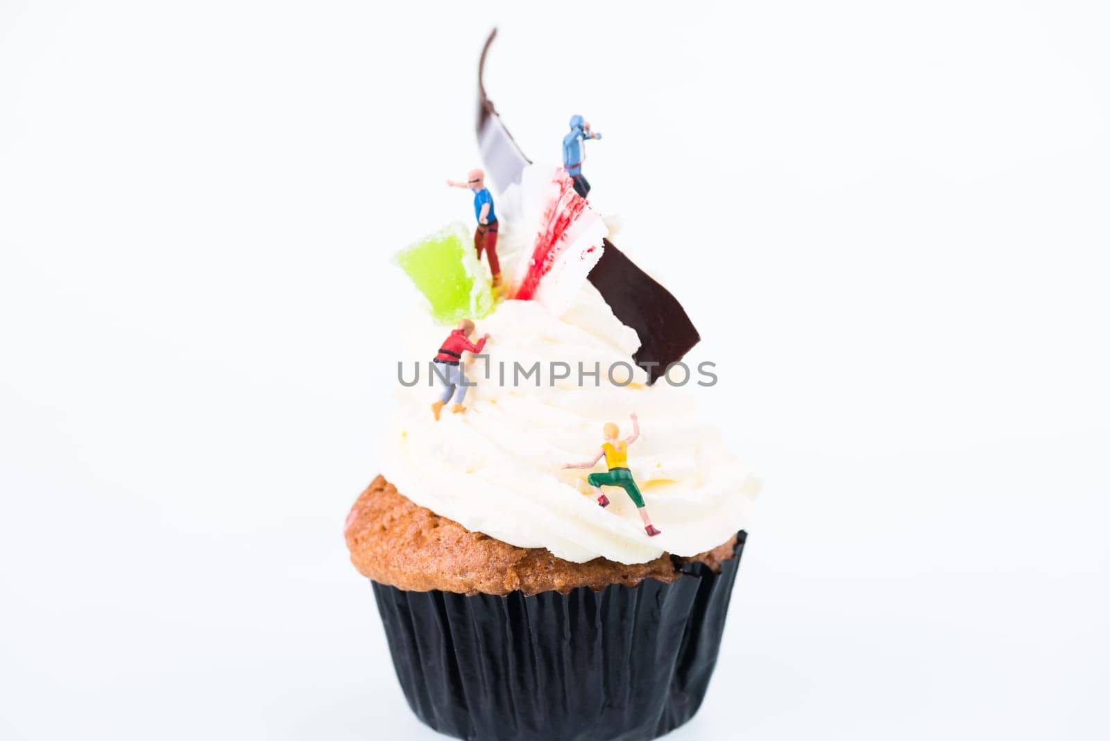 Concept of sugar high or sugar rush with miniature people going up the frosting of cupcake