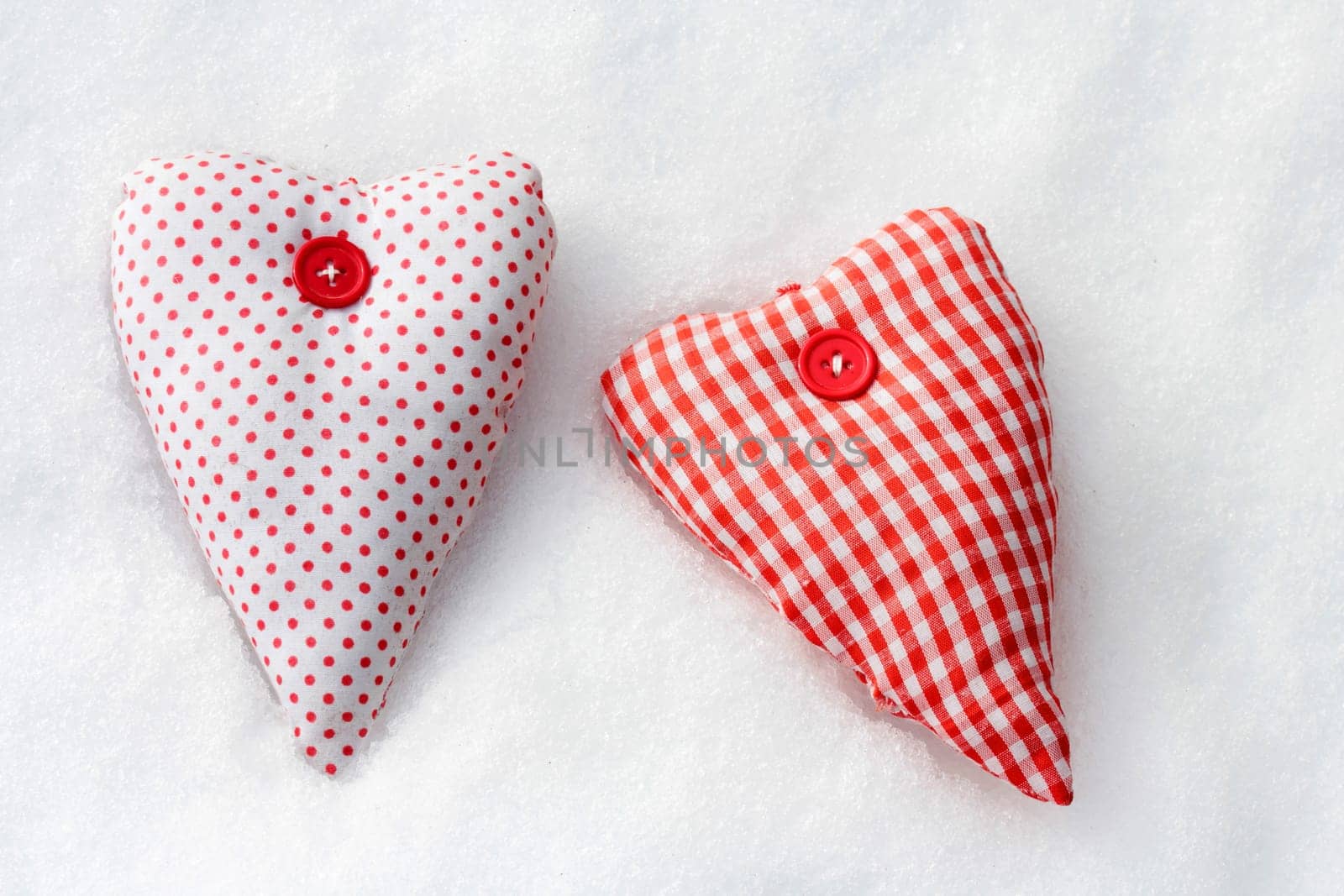 Two red and white hearts made of fabric in the snow