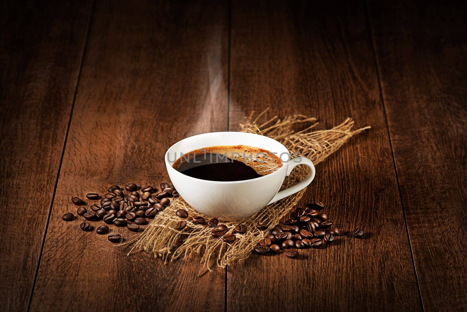 Coffee cup with smoke and beans on wooden table. Copyspace for your text