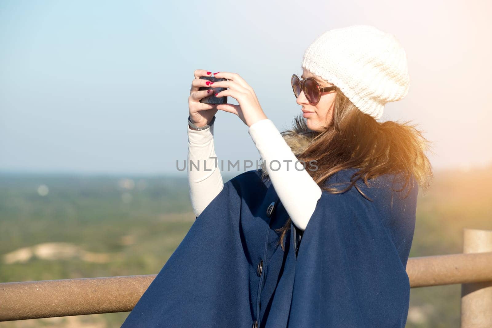 Beautiful happy young girl posing outdoors with phone