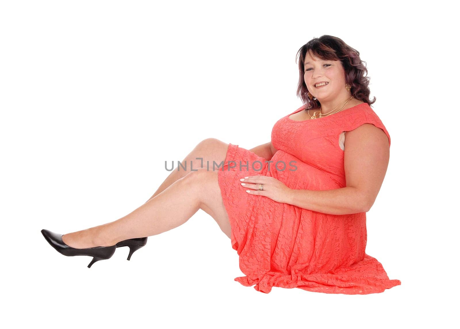 A beautiful big woman sitting in a red dress in the floor, smiling into.the camera, isolated for white background.