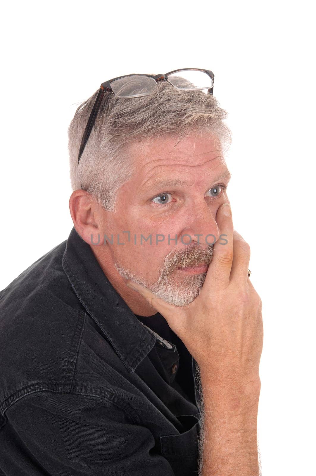 A gray hared middle aged man sitting isolated for white background with.his hand on chin and glasses on his head, isolated for white background.