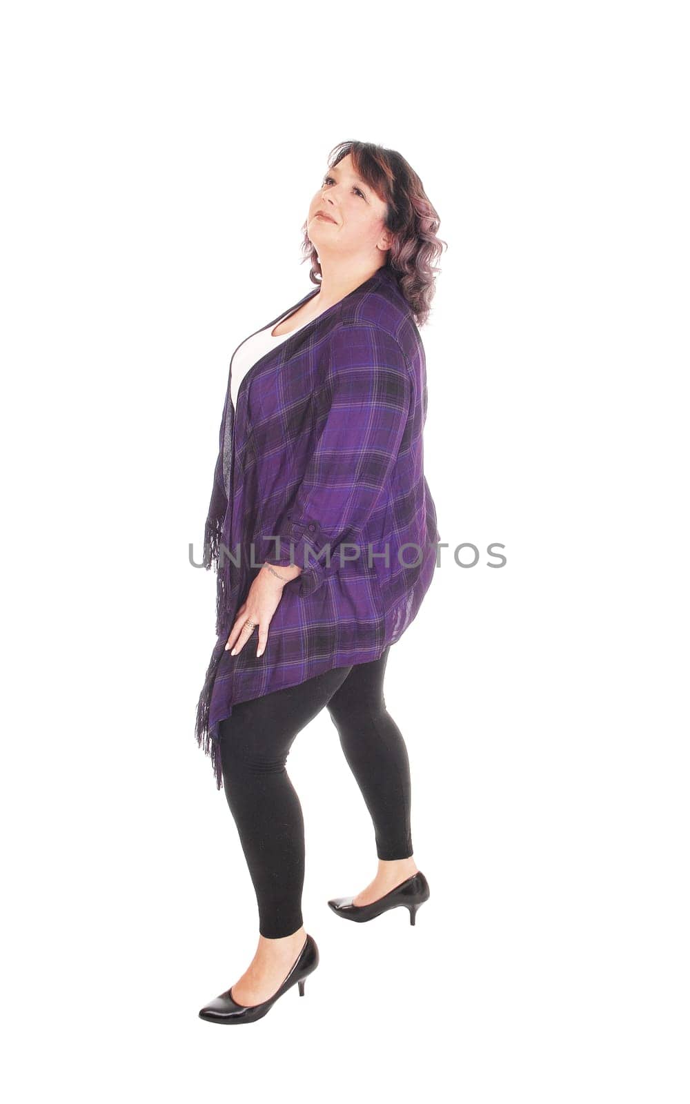 A lovely overweight woman in her forties standing in profile in tights,.looking up, isolated for white background.