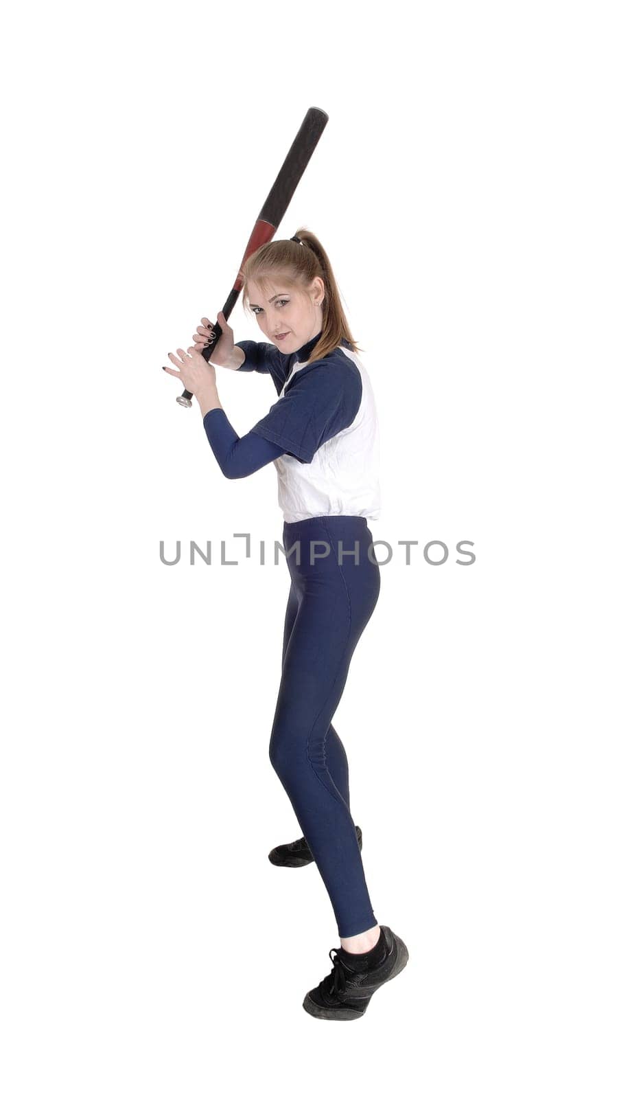 A young slim woman playing softball, swinging her bad to hit the ball.in a blue uniform, isolated for white background.