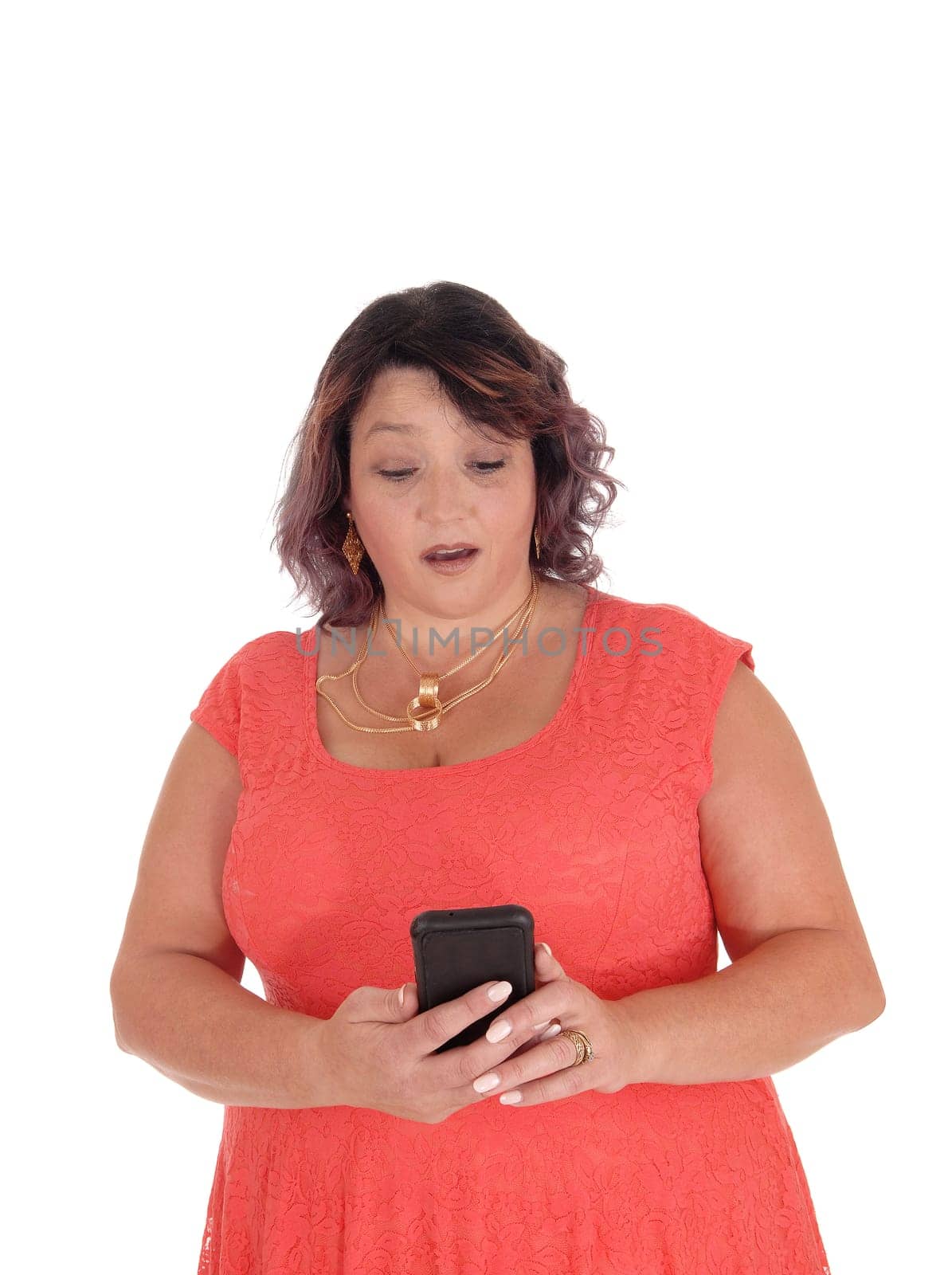 A lovely big woman in a red dress standing isolated for white .background looking very surprised at her smart phone..