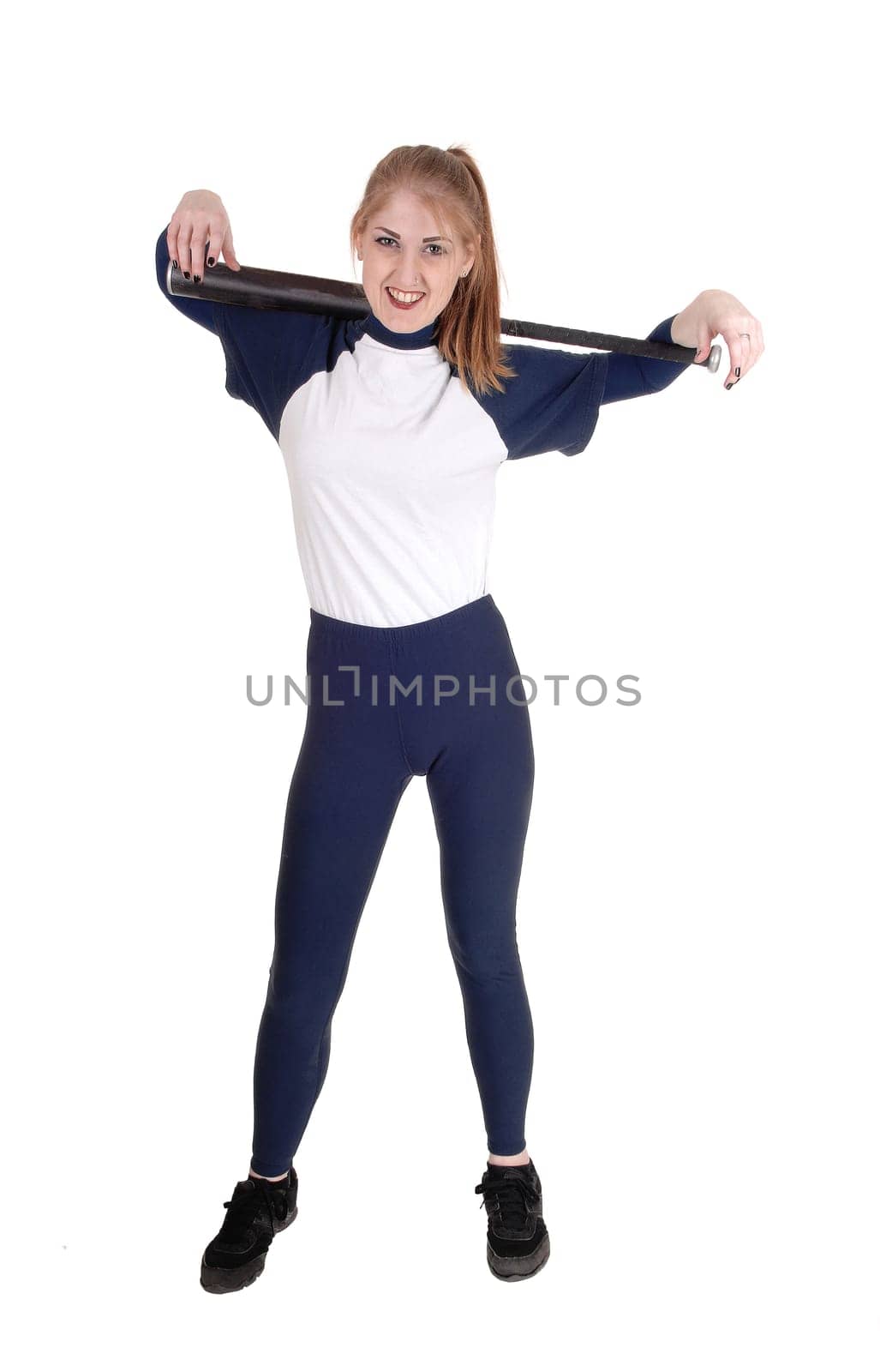 A young slim woman playing softball, holding her bad and smiling.in a blue uniform, isolated for white background.
