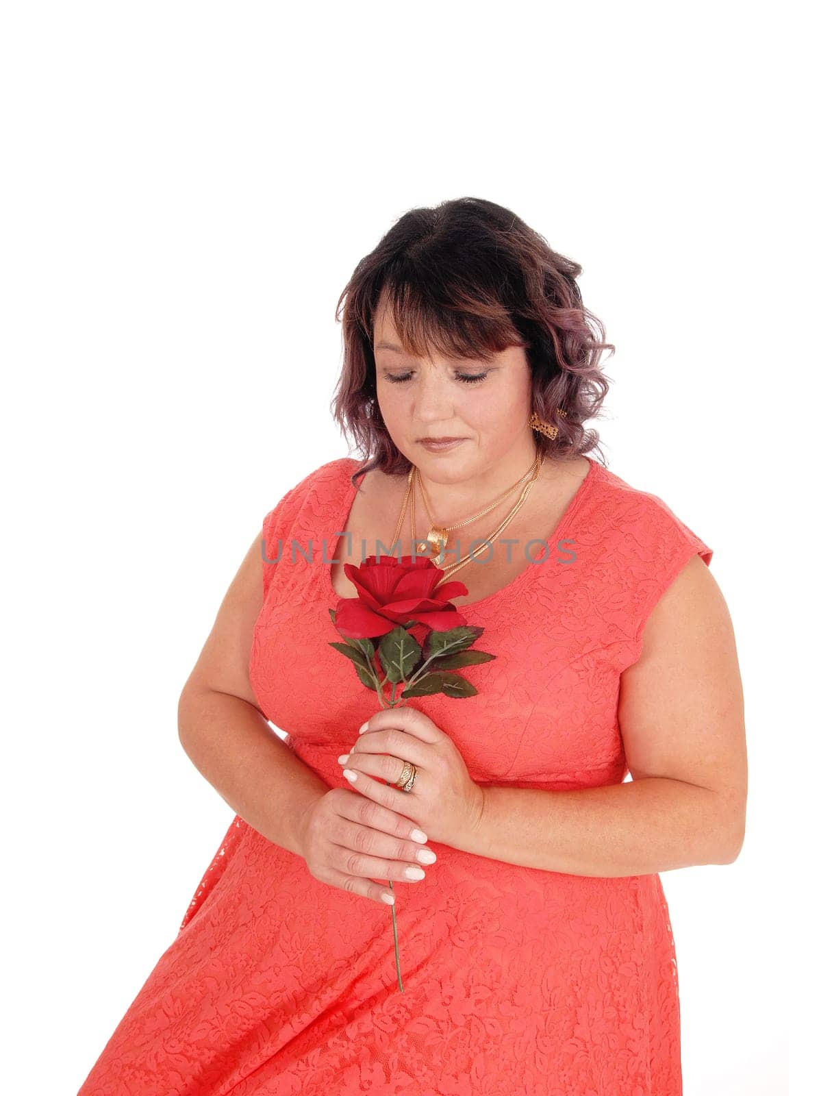 A close up image of an plus size woman in a red dress holding a red.rose, with necklace, isolated for white background.