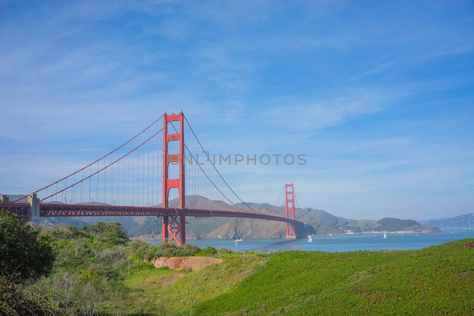 San Francisco Golden Gate Bridge Landscape, with a blue sky and green foliage in the foreground.
