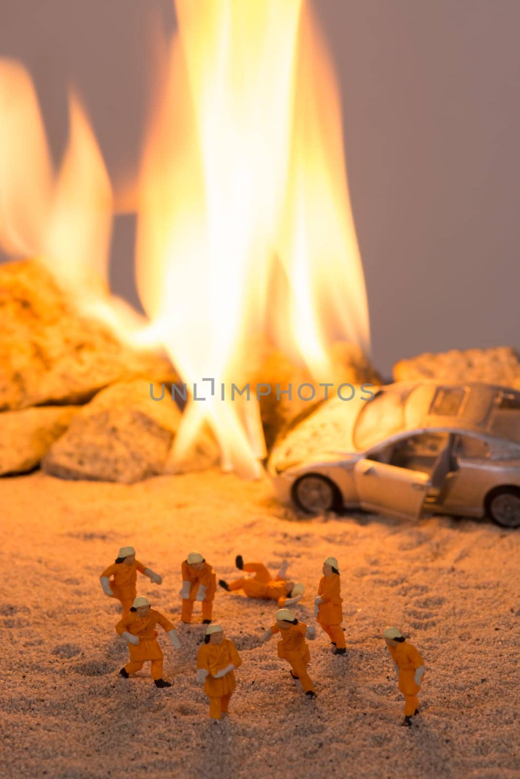 Miniature firefighters at a car accident scene in flames