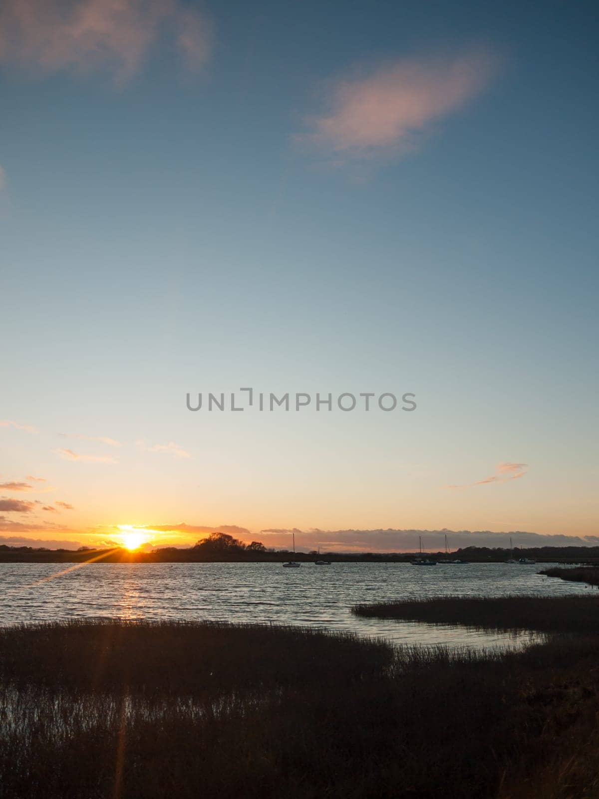 sun setting horizon blue water sky surface silhouette coast ocean waves  essex  england  uk