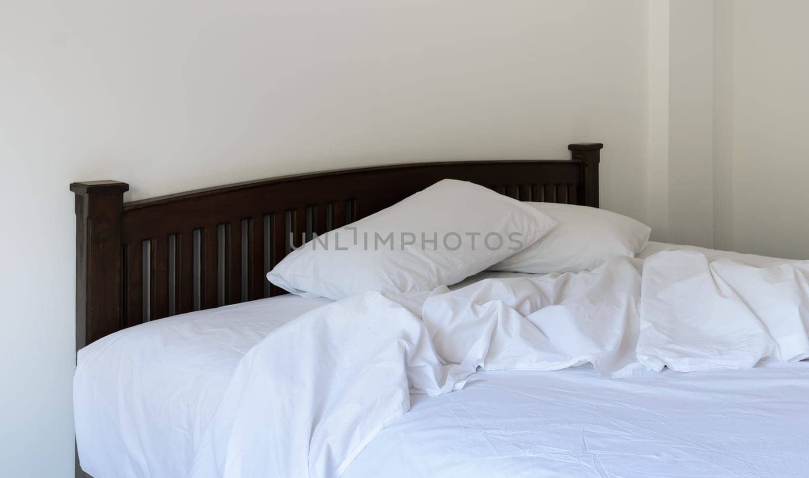 Morning view of an unmade bed in white bedroom
