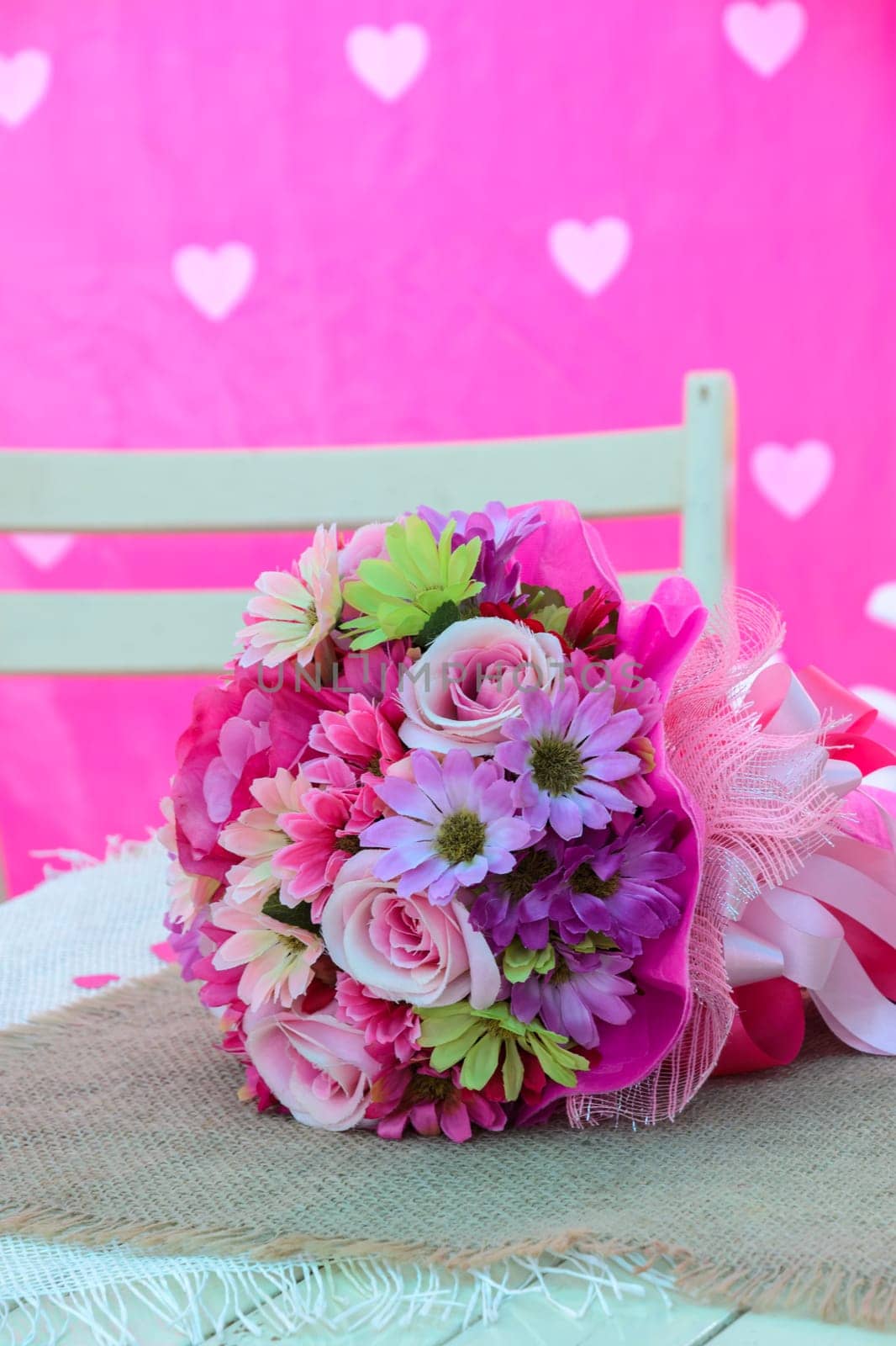Artificial bouquet flowers on white table with pink background. Valentine concept image.