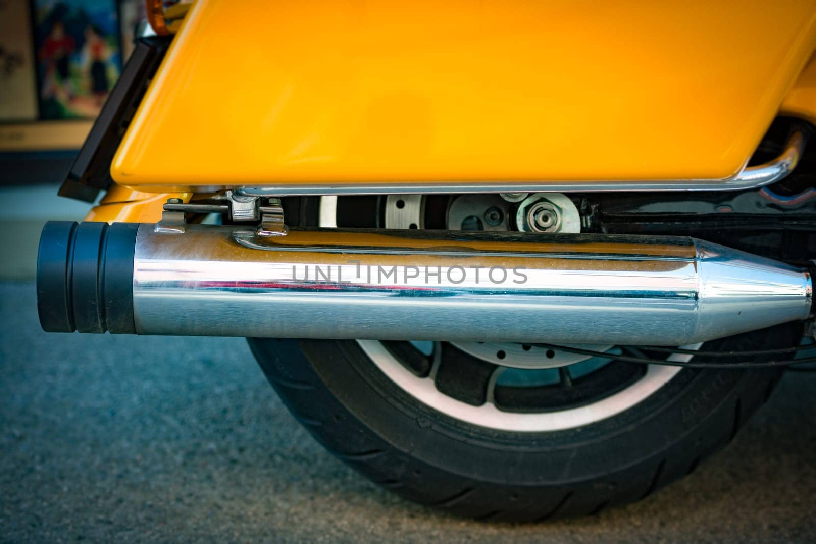 Close up view of motorcycle wheel and exhaust pipe in street