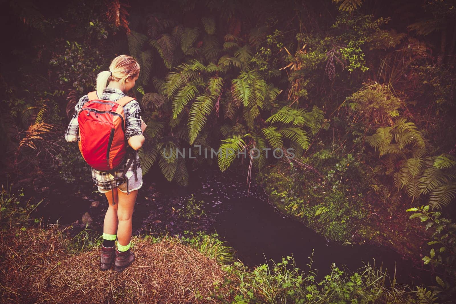 Beautiful young woman hiking by stream