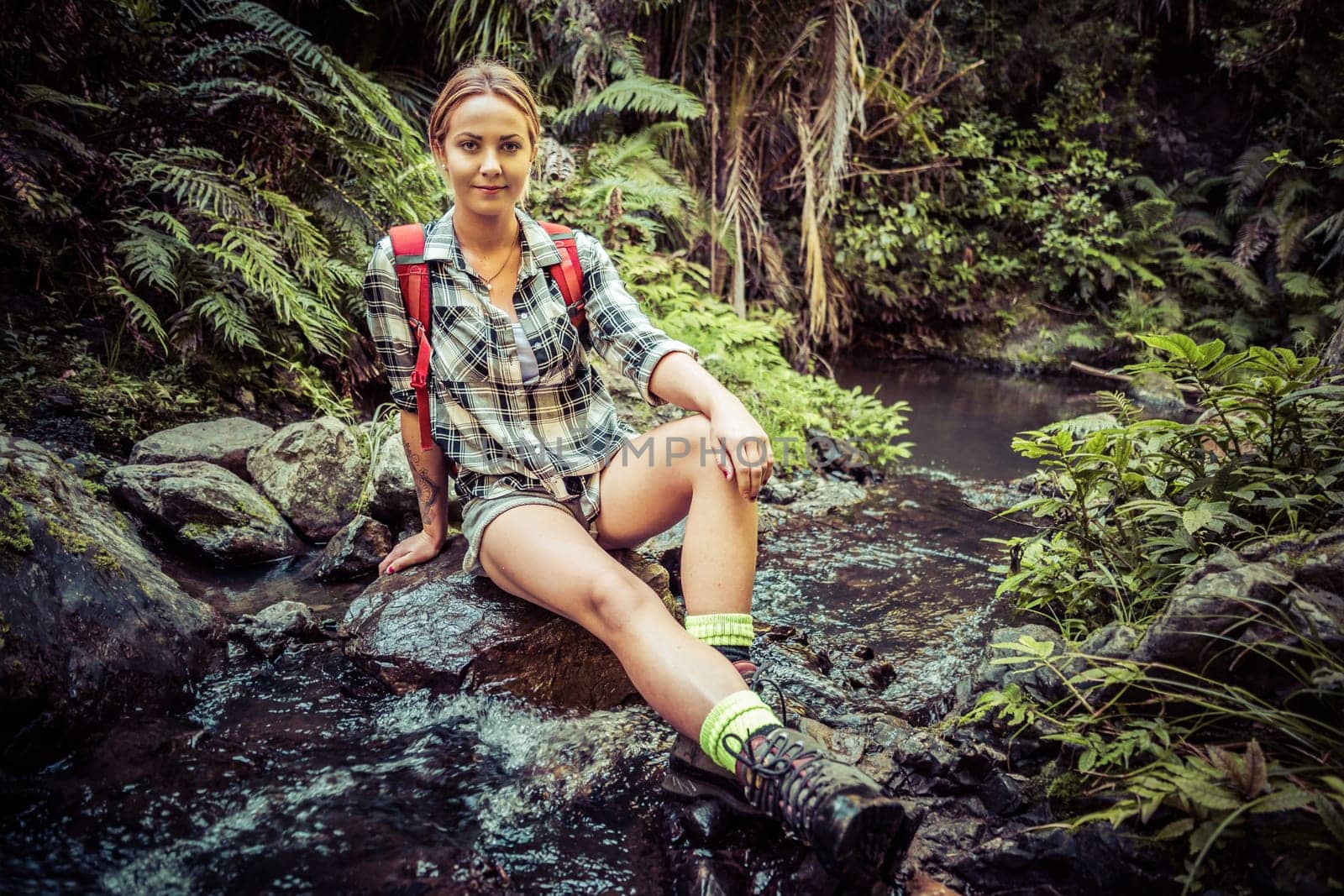 Beautiful female hiker sitting by stream