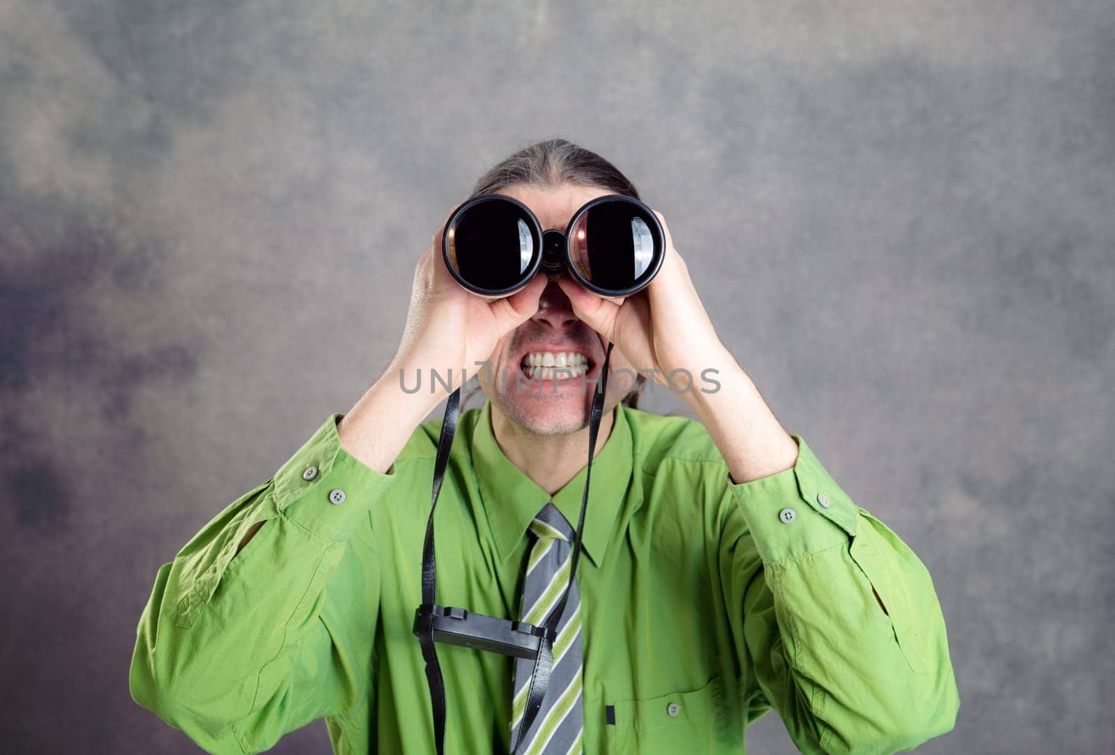 young man in green shirt and necktie looking through a binoculars