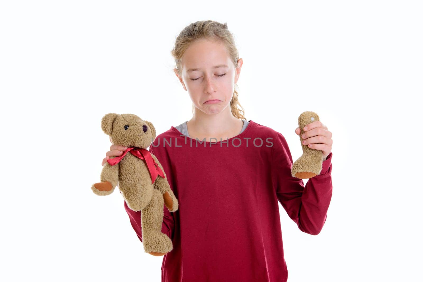 blond girl with broken teddy bear in front of white background
