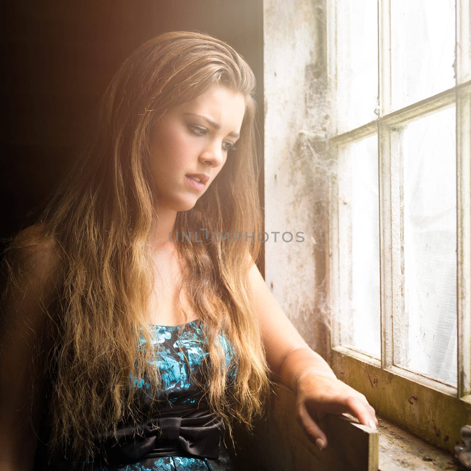 Sad young woman by window