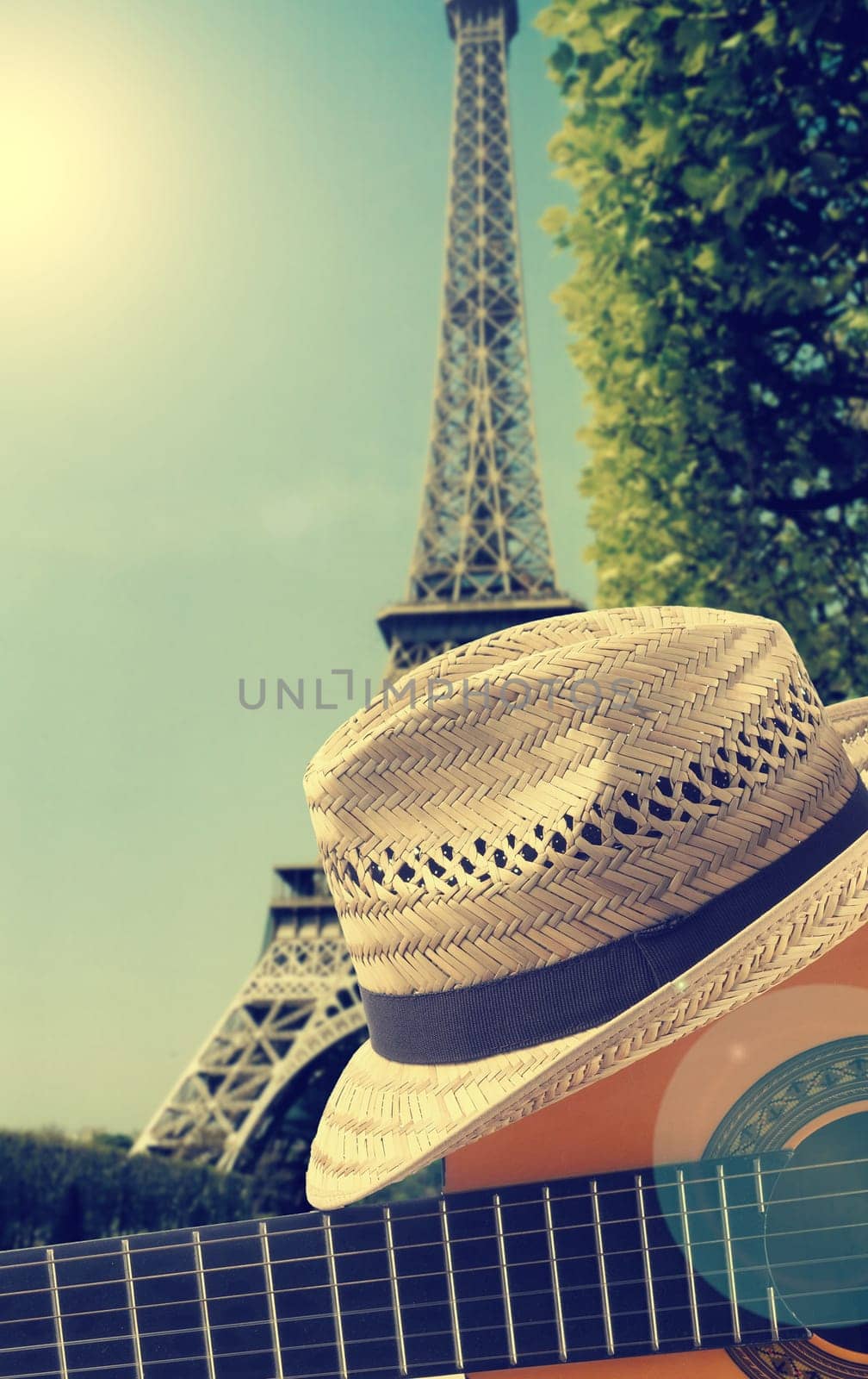 Vacation or travel concept with guitar and summer hat in front of the Eiffel Tower in France, vintage photo stylized