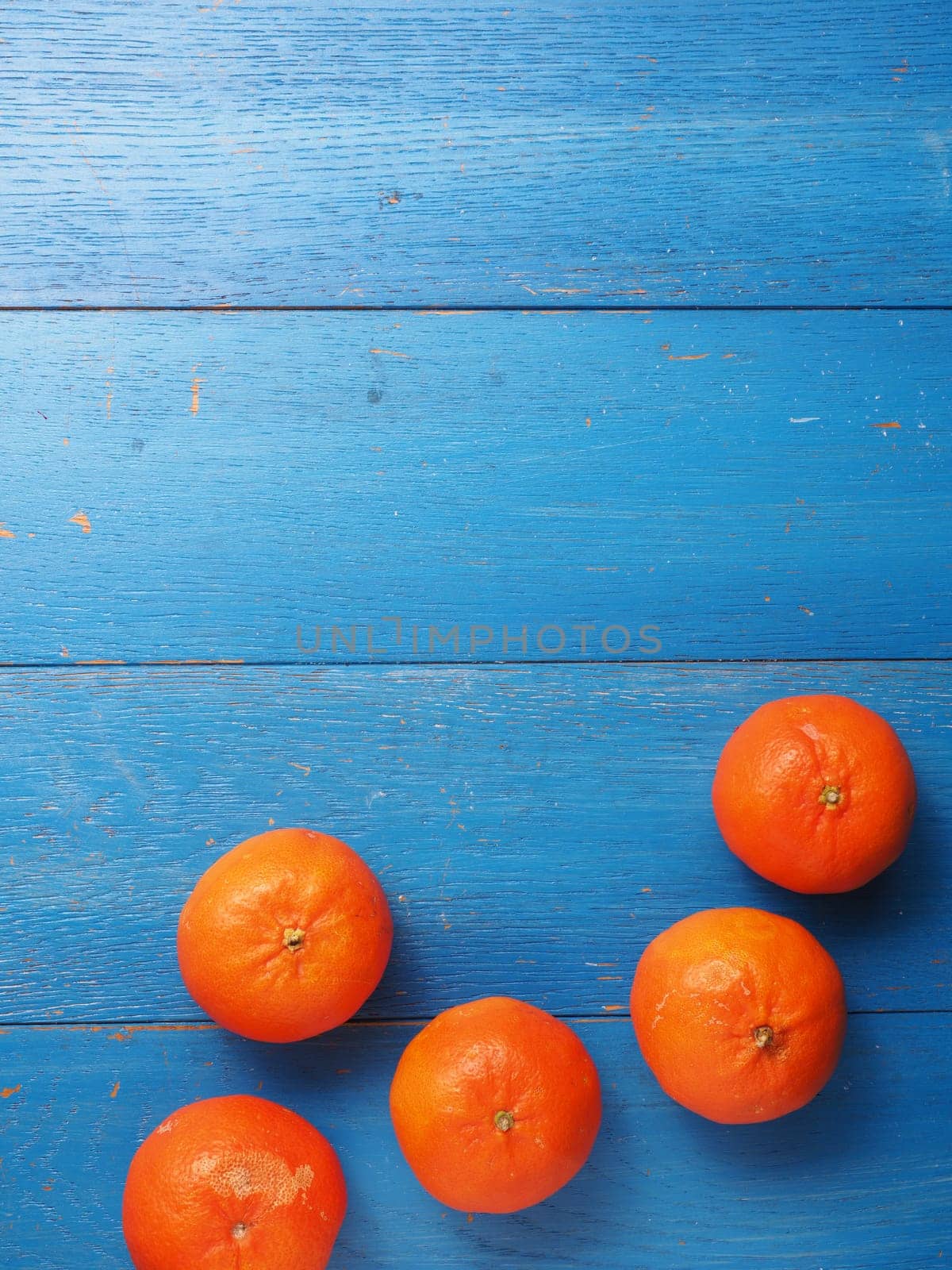 Fresh organic tangerine fruits on a blue weathered wooden table