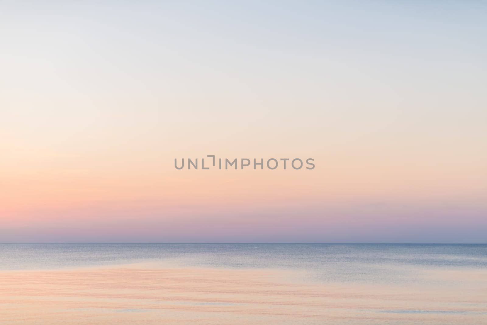 Horizontal picture of clouds in the sky above calm sea surface during sunset