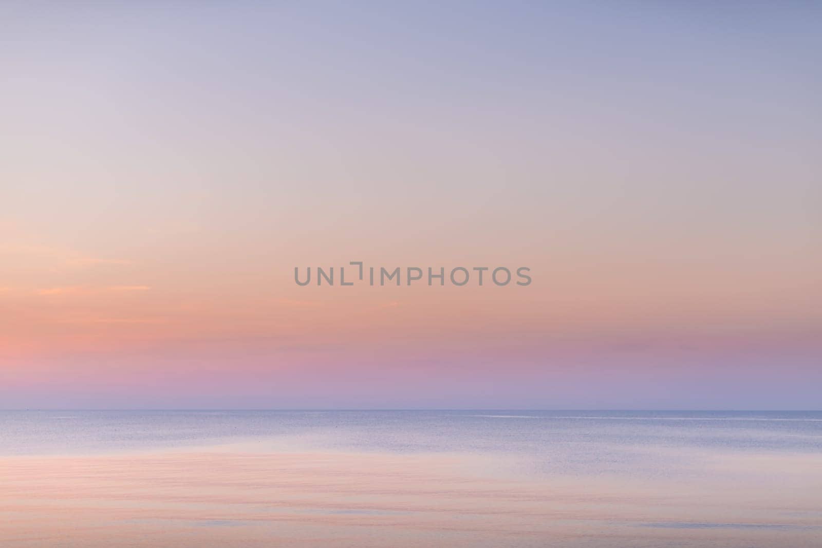 Horizontal picture of clouds in the sky above calm sea surface during sunset