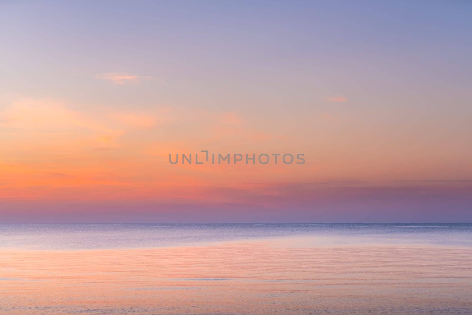 Horizontal picture of clouds in the sky above calm sea surface during sunset