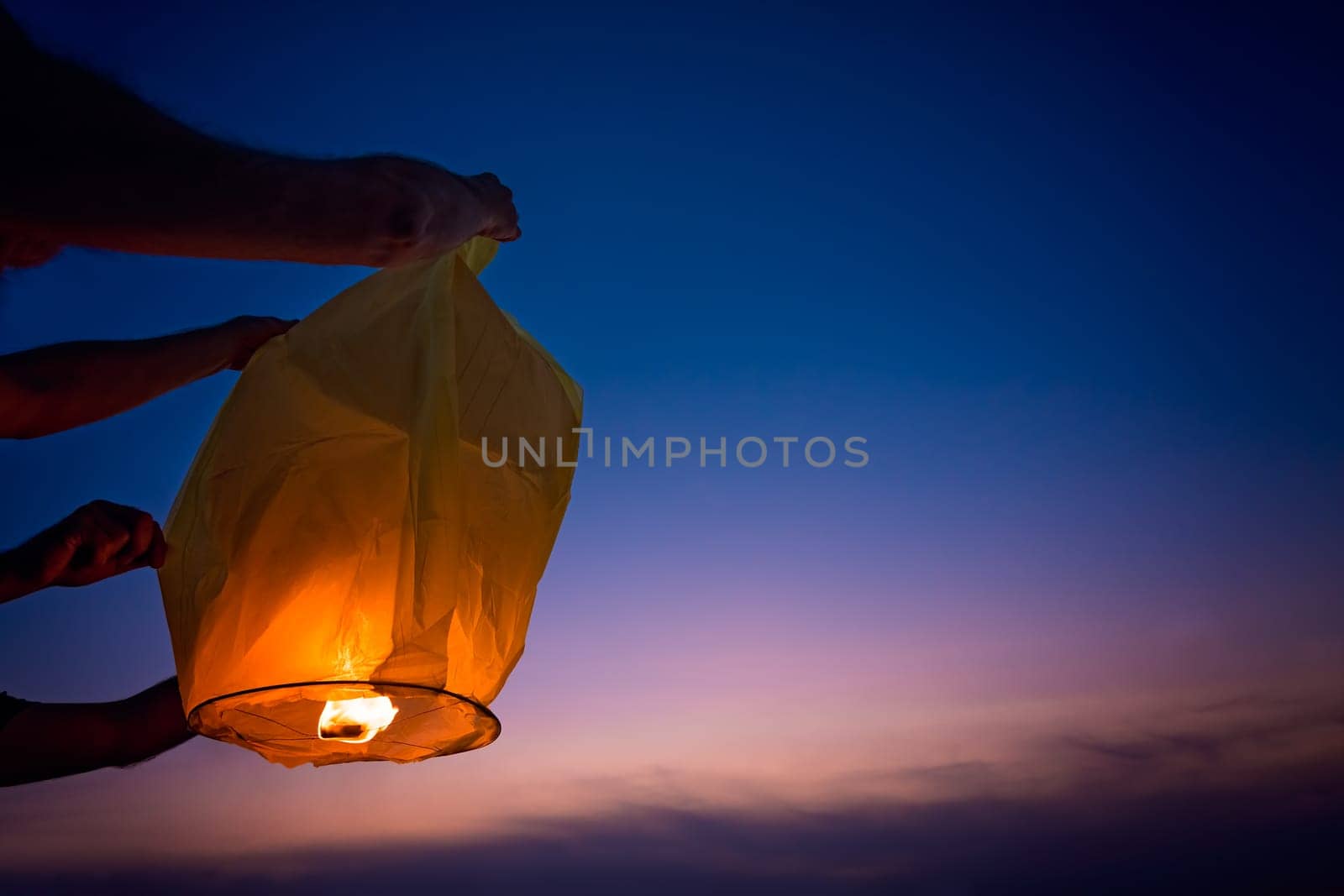 People setting off chinese lantern on the beach at sunset