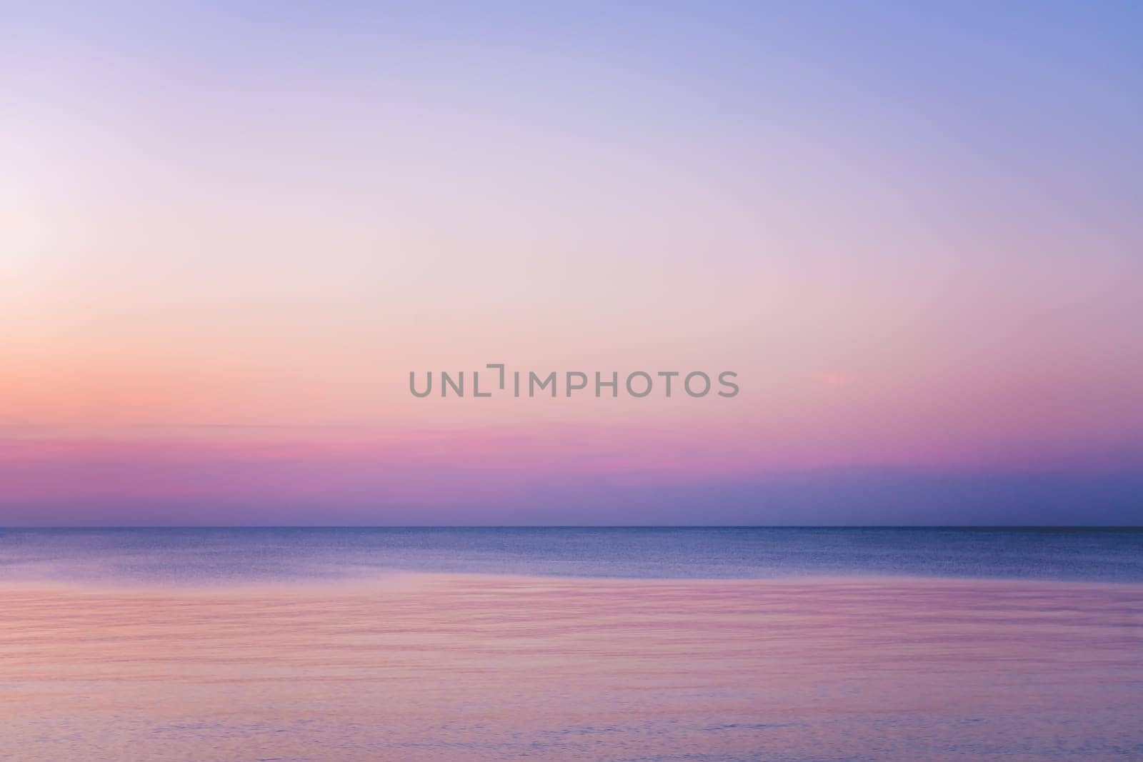 Horizontal picture of clouds in the sky above calm sea surface during sunset