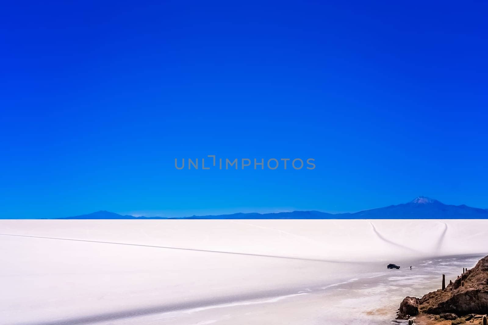 Four wheel car with touriusts in front of the Cactus island in the middle of Salar de Uyuni in Bolivia