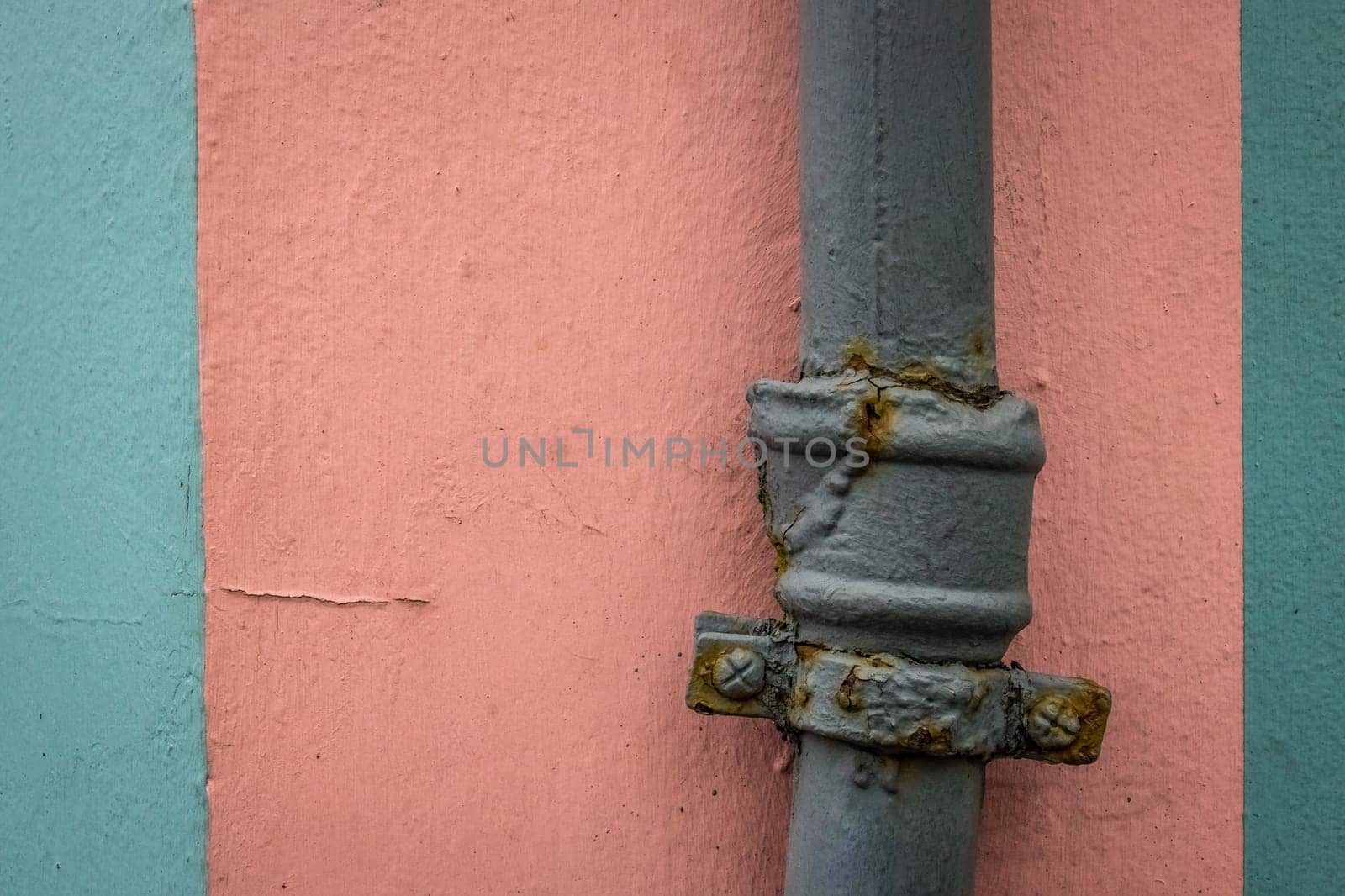 Old rusted water pipe on pink and blue wall texture background