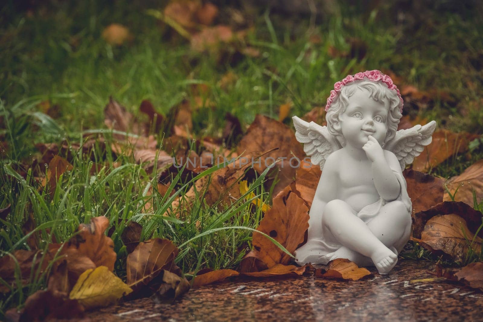 Tiny angel figure next to a child grave in cemetery