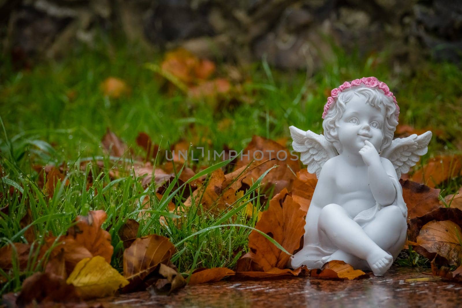 Tiny angel figure next to a child grave in cemetery