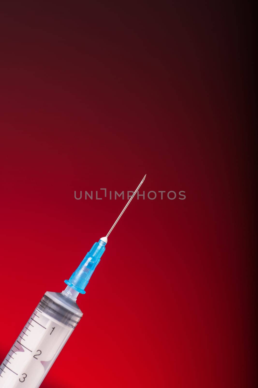 Isolated medical syringe on red, dark background