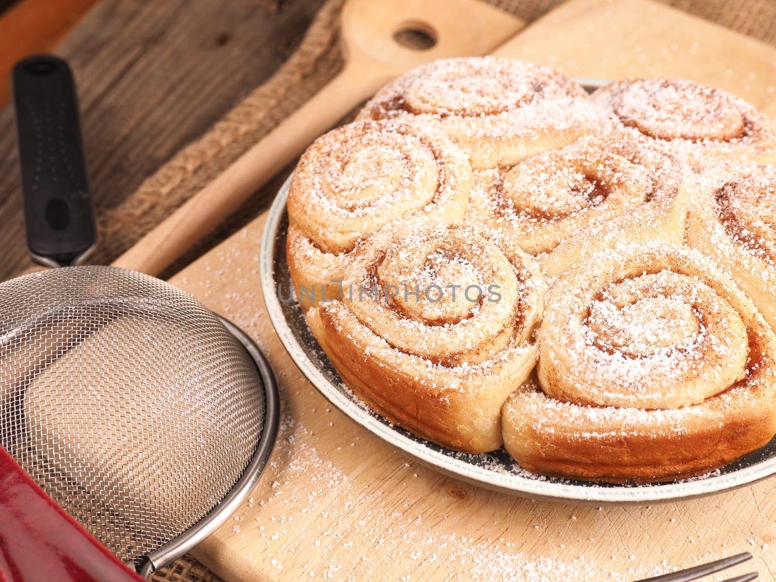 Homemade cinnamon snails with kitchen utensils on a rustic wooden kitchen table