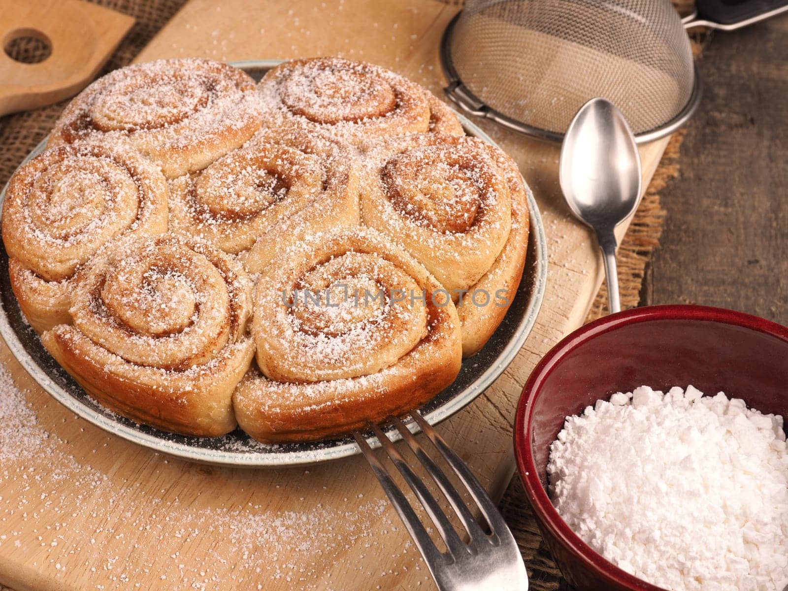 Homemade cinnamon snails with kitchen utensils on a rustic wooden kitchen table