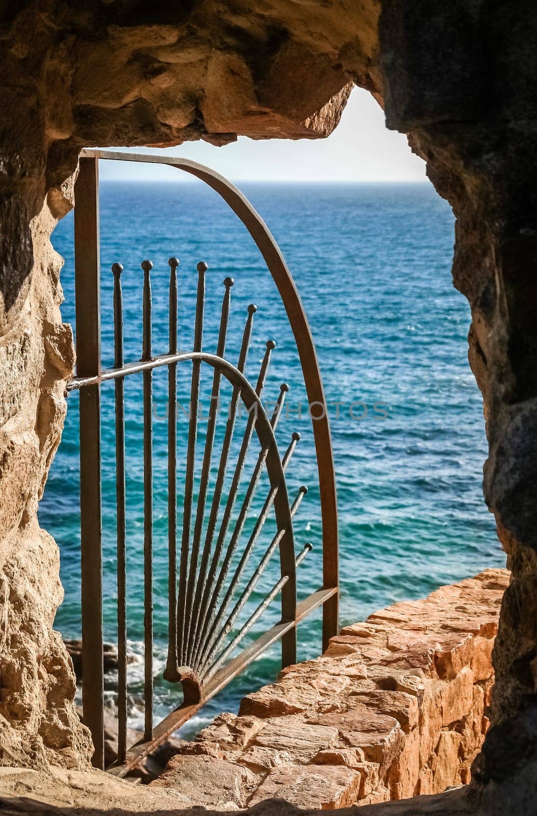 Closeup of protective railings on ocean wall viewed though stone window.