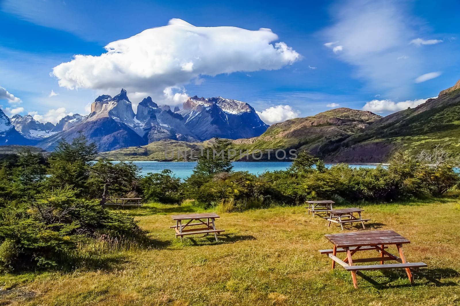 Wooden picnic tables on the grass on the camping site near the stunning Cuernos del Paine, Patagonia, southern Chile