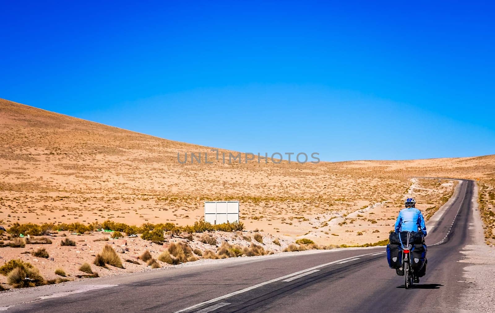 Woman cycling on the empty road to Parc National Lauca located on the border between Chile and Argentina, South America