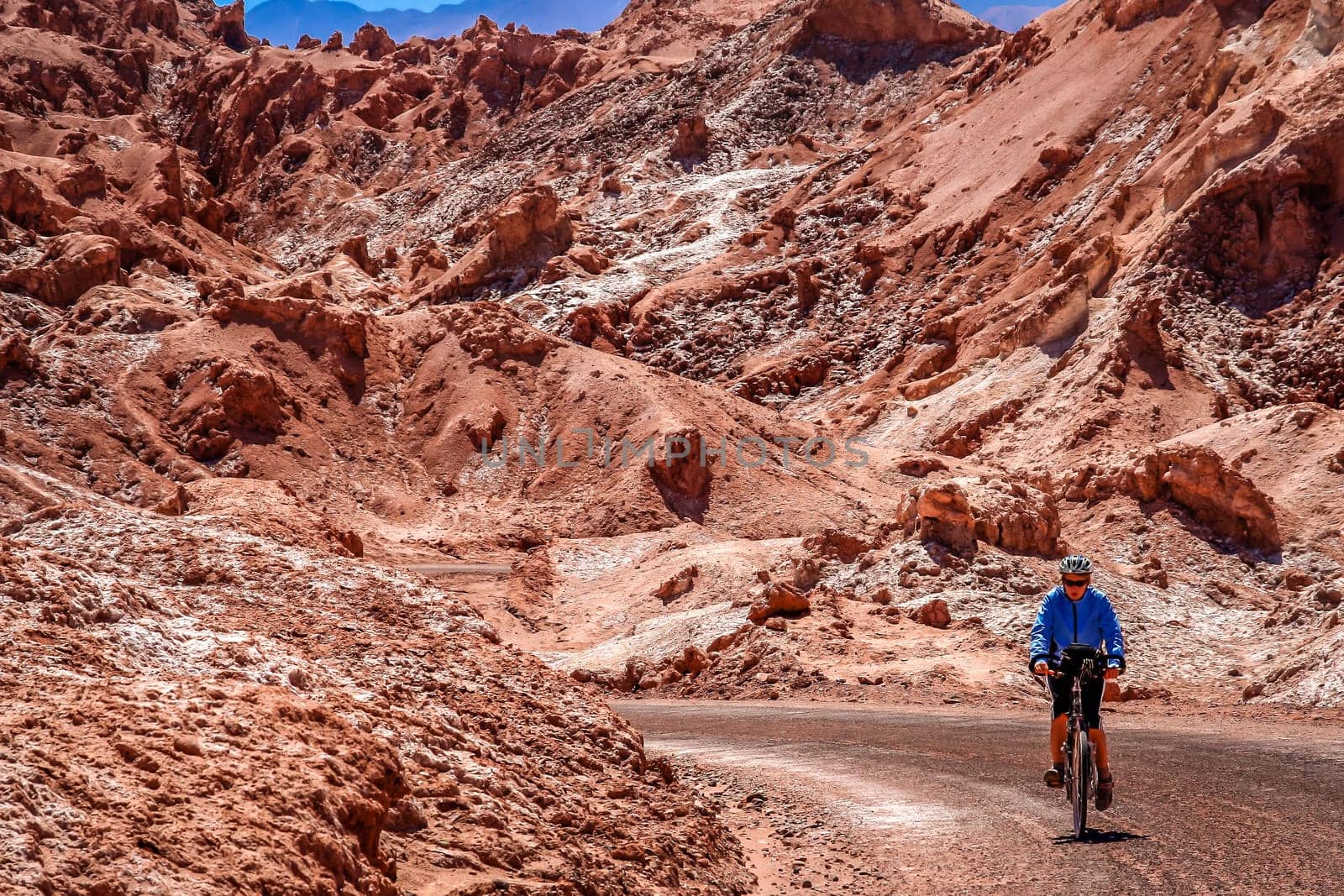 Female cyclist traveling on the road through the famous Valle the la Luna near San Pedro de Atacama, Chile, South America