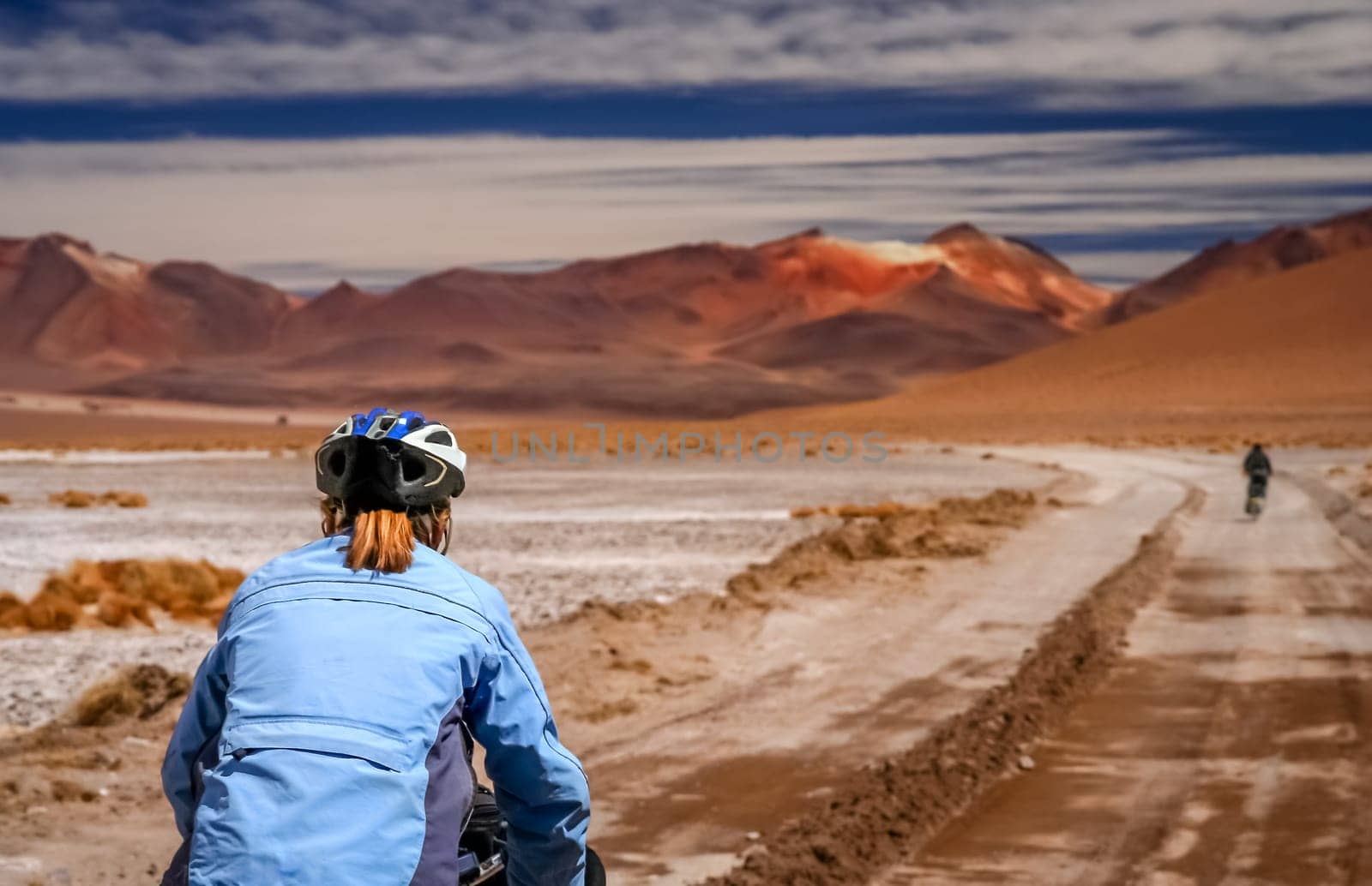 Woman cycling on the sandy road in Altiplano in Bolivia