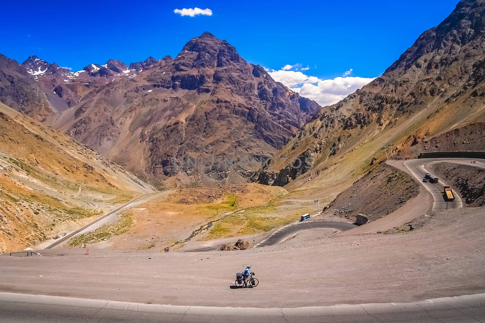 Female cyclist riding downhill on the twisting and turning switchbacks on the beautiful road through high Andes from Artgentina to Chile, South America