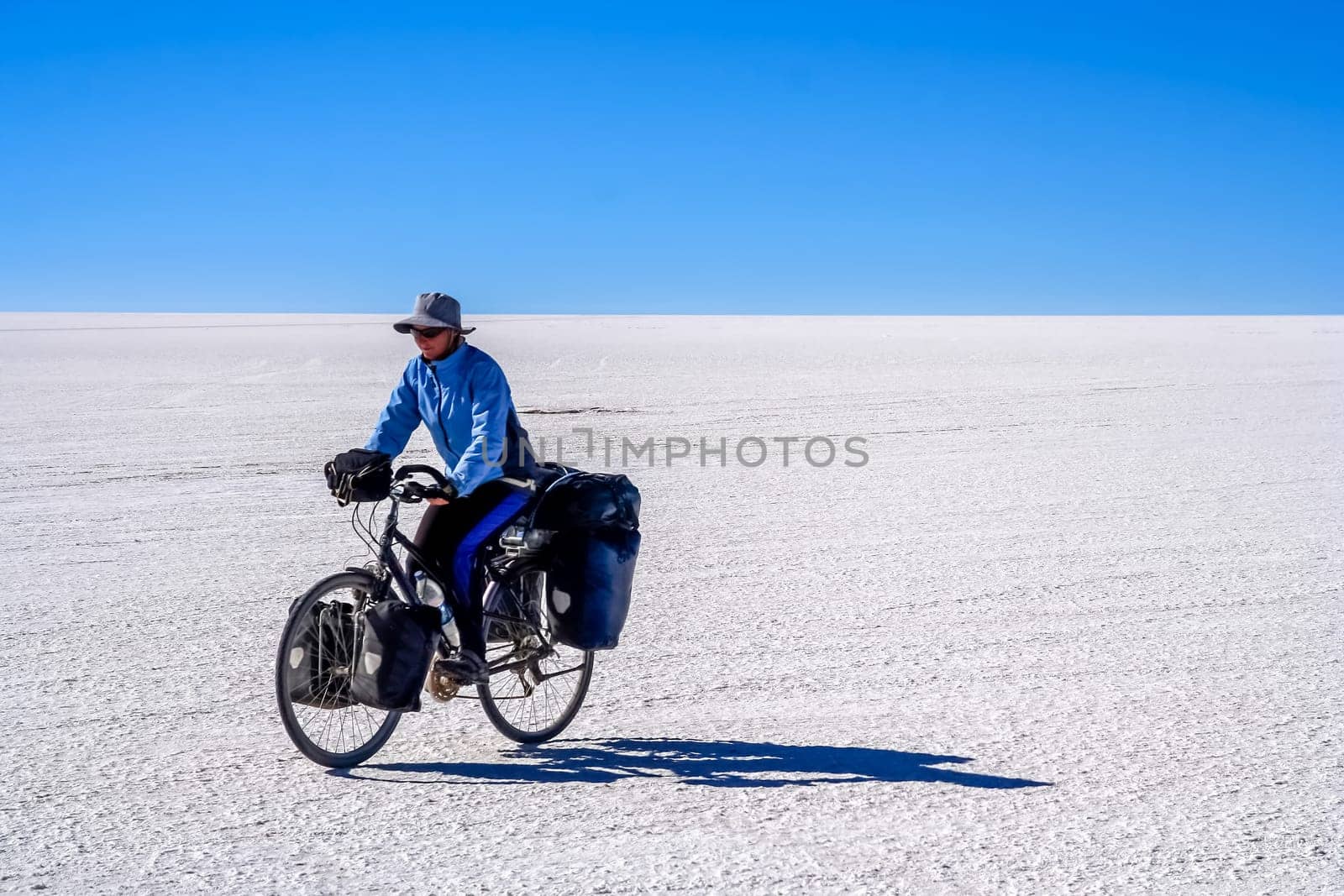 Lonely female cyclist travelling solo through the Salar de Uyuni in Bolivia, the biggest salar in the world