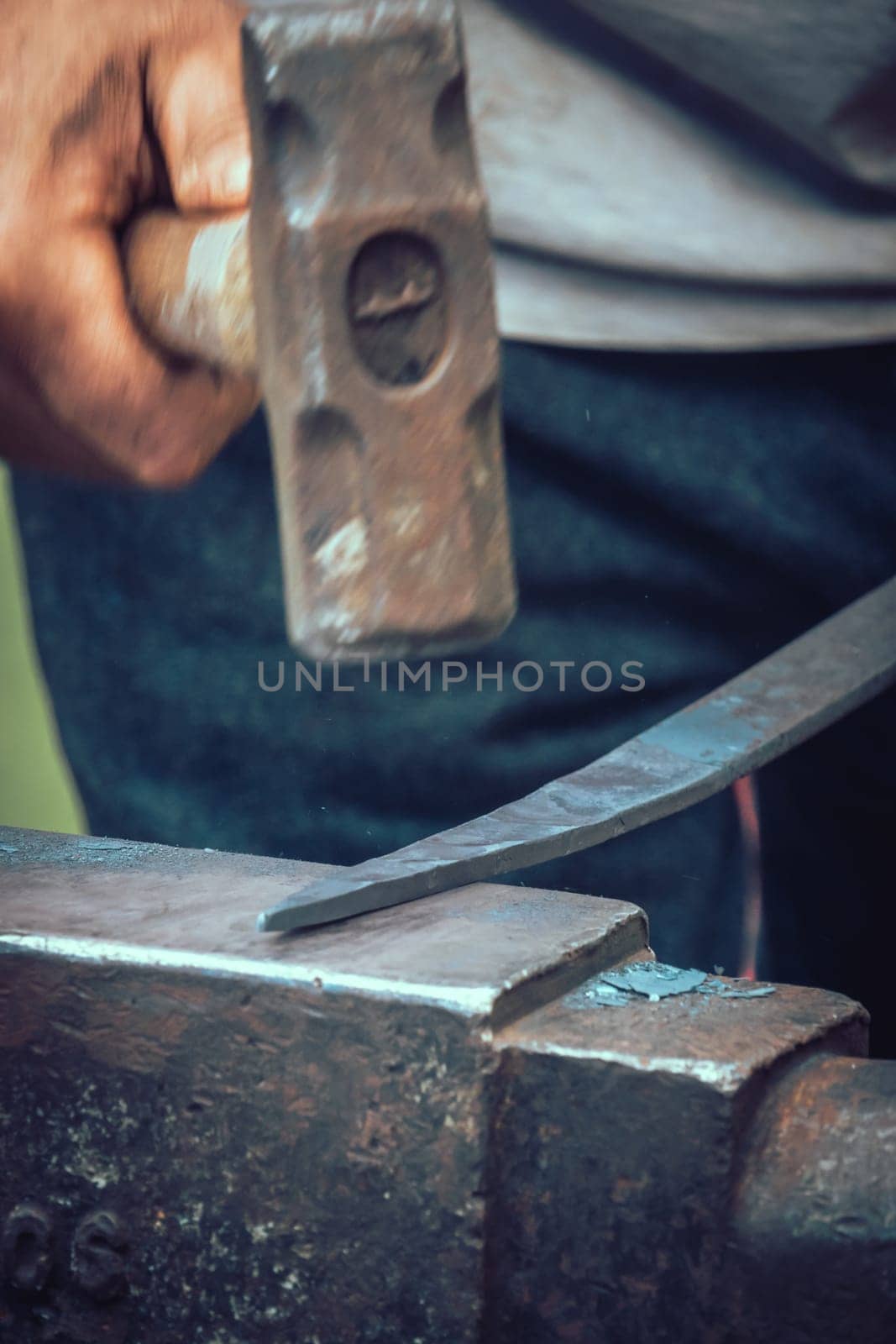 A blacksmith hammering hot iron during medieval fair festival in Streatham Park in London