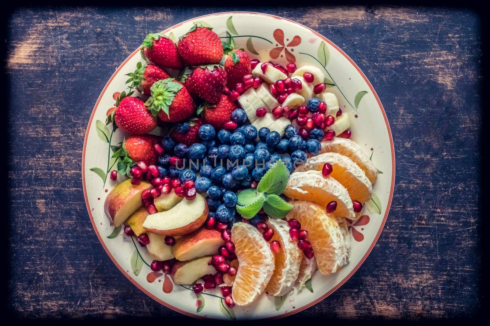A closeup view of a platter of mixed fruits including strawberries, oranges, blueberries, apples and bananas